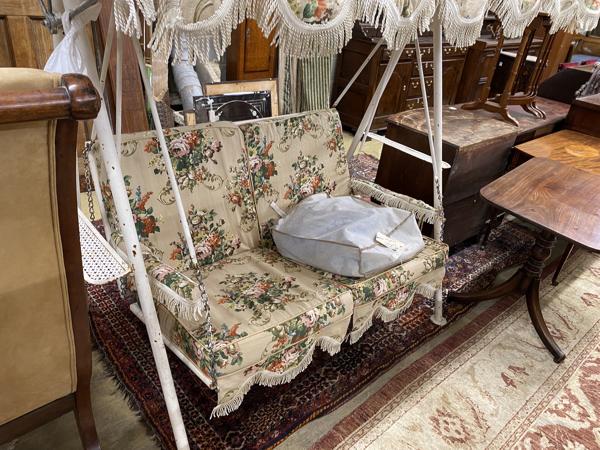A vintage metal garden swing seat with printed floral covers, width 170cm, depth 104cm, height 180cm